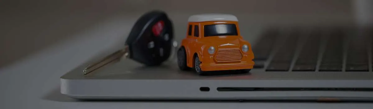 coche naranja de juguete encima de un ordenador al lado de unas llaves